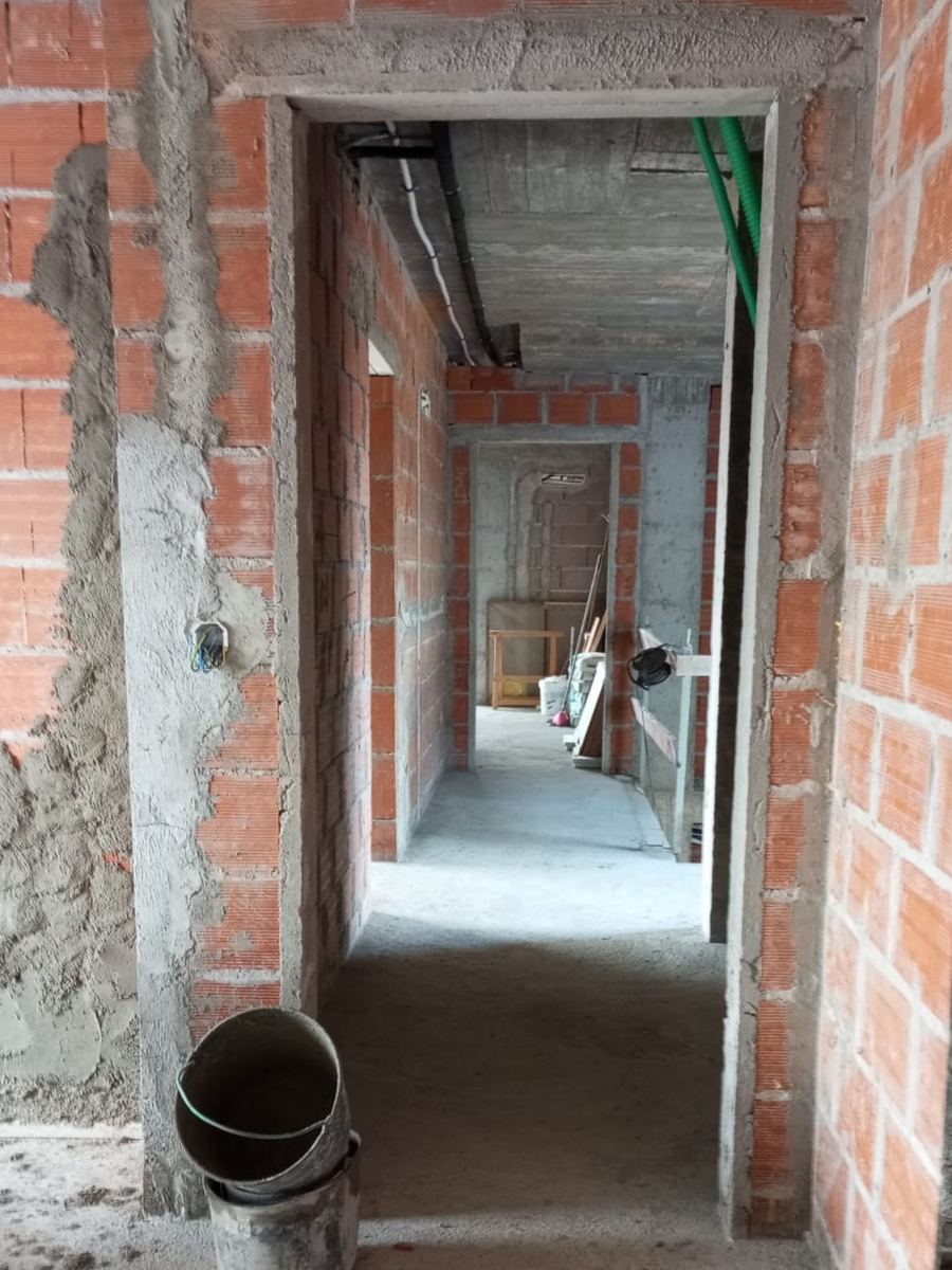 Corredor em obra, paredes em tijolo e entulho no chão