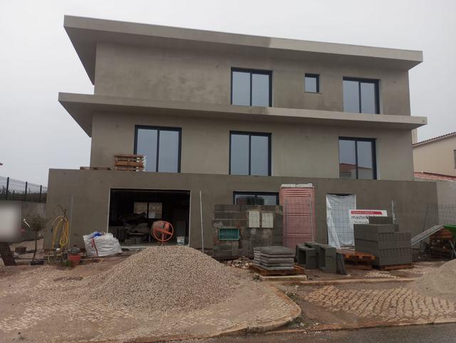 Fachada da moradia em construção, com estrutura e caixilharia já colocadas